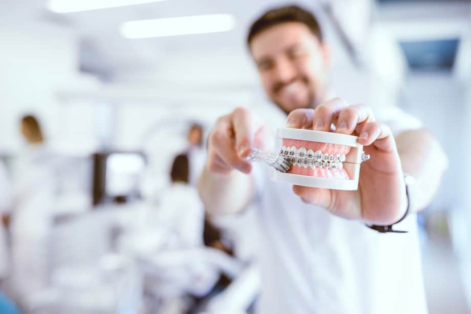 a dentist brushes a model of teeth with braces