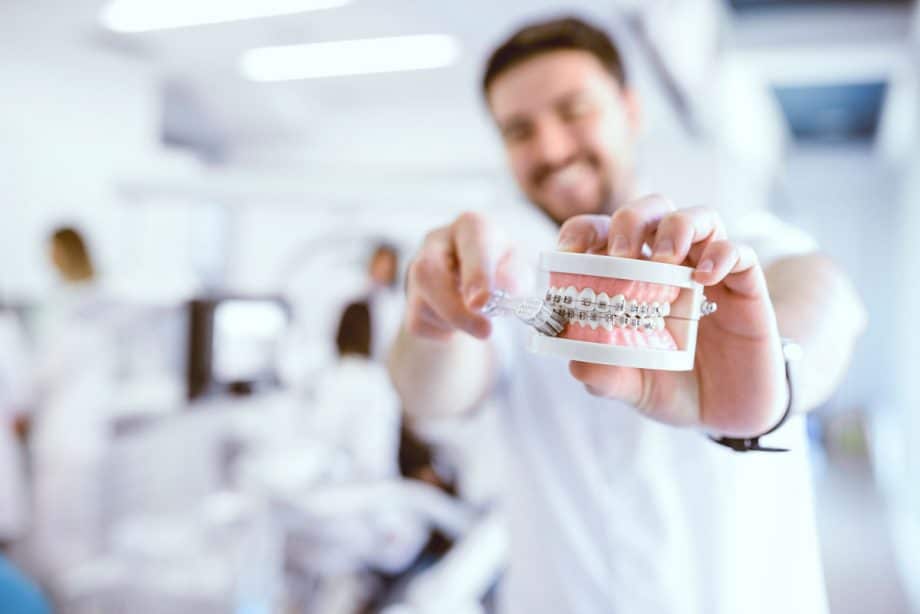 dentist brushing teeth on model with braces