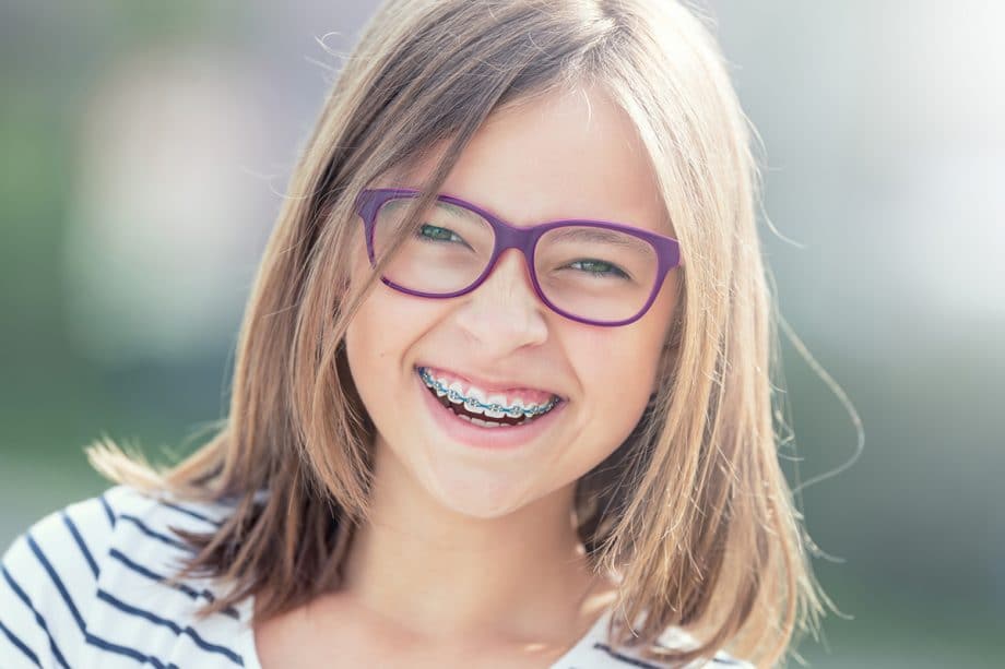 a girl with braces and glasses smiles