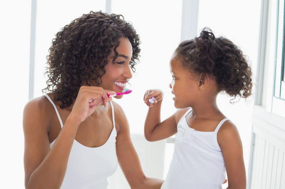 mom and young daughter brushing teeth together