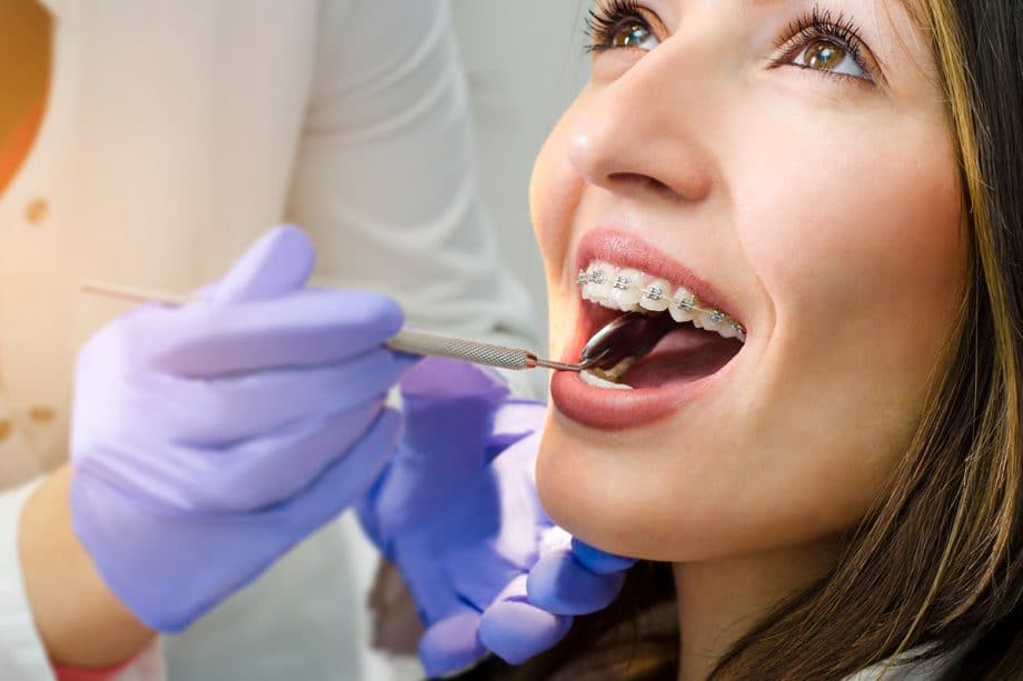 dentist examines the teeth of a girl with braces