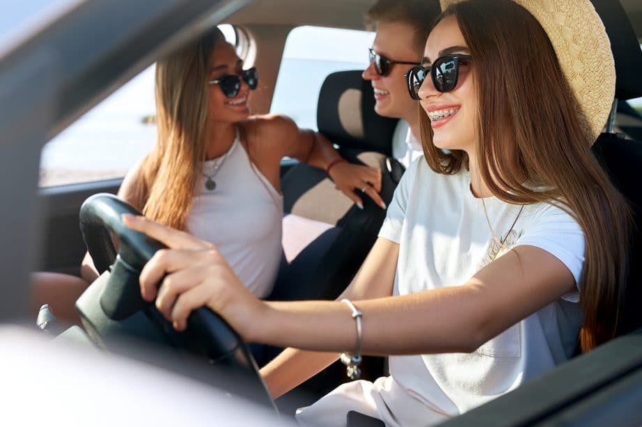 three teens with sunglasses on laugh in a car