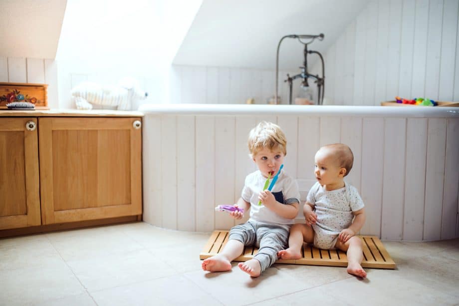 two young children play with toothbrushes